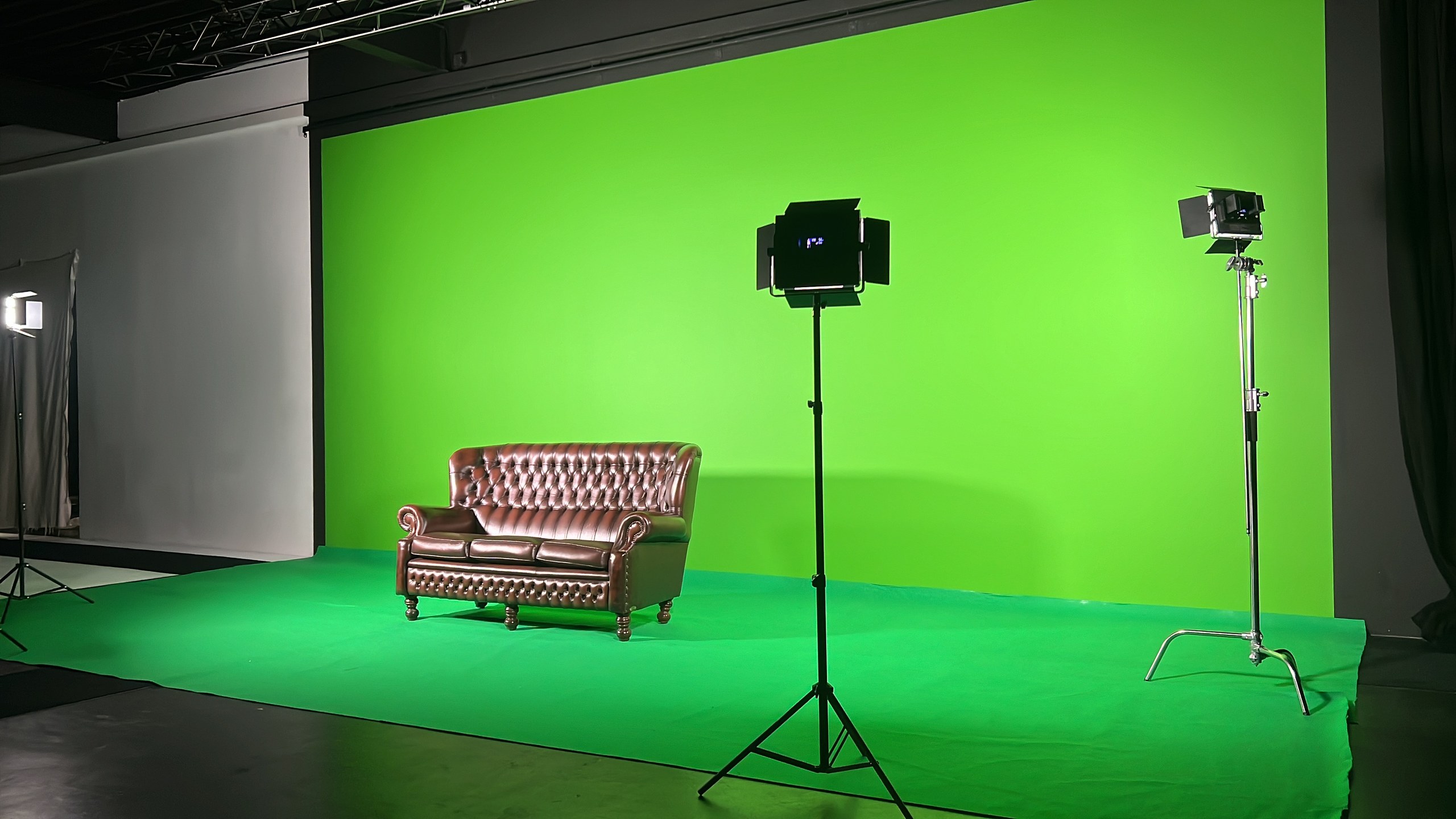 Greenscreen-Wand und Teppich mit Chesterfield-Sofa und zwei Leuchten, 16:9
