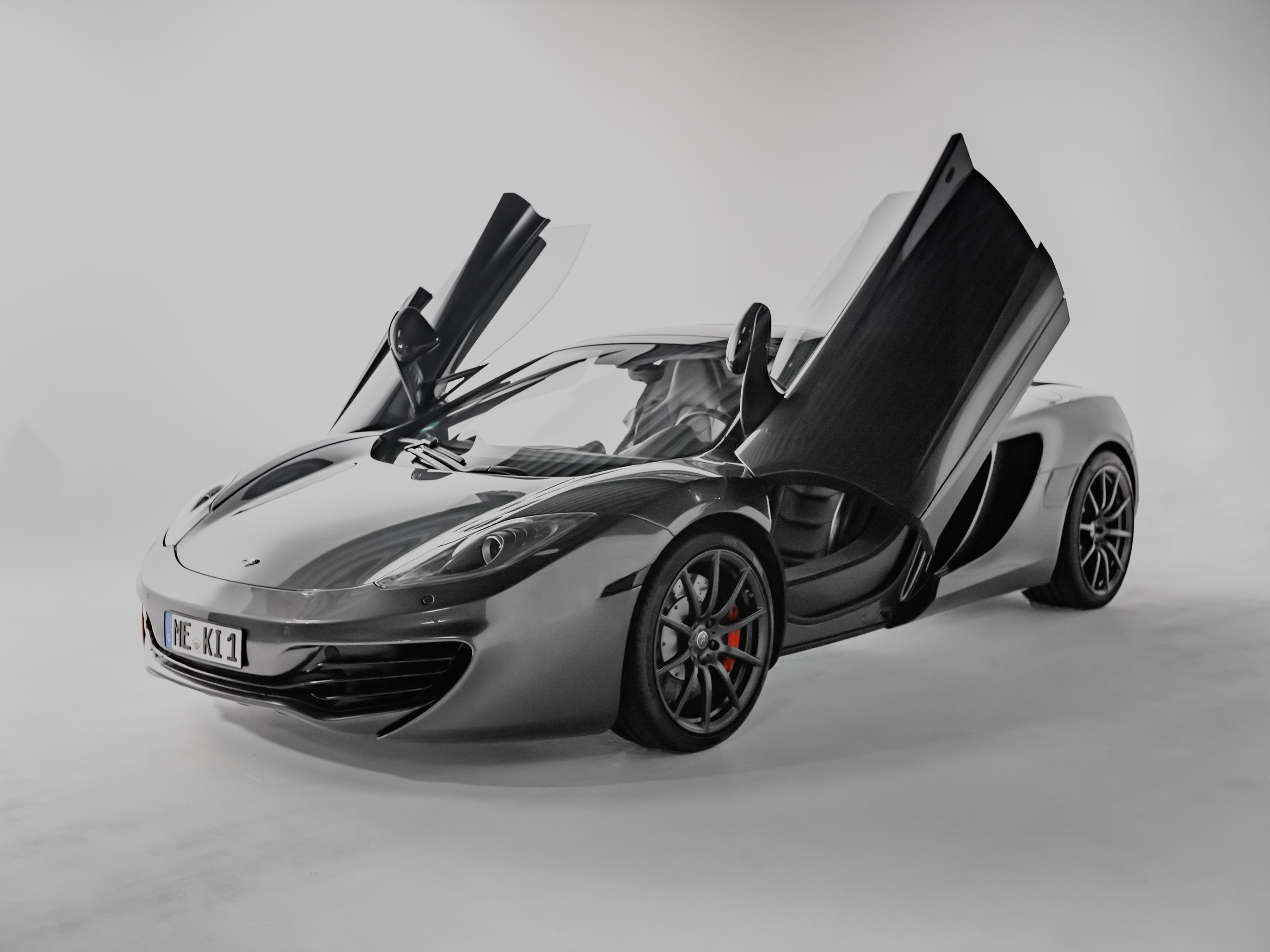Supercar mit offenen Flügeltüren in der weißen Hohlkehle