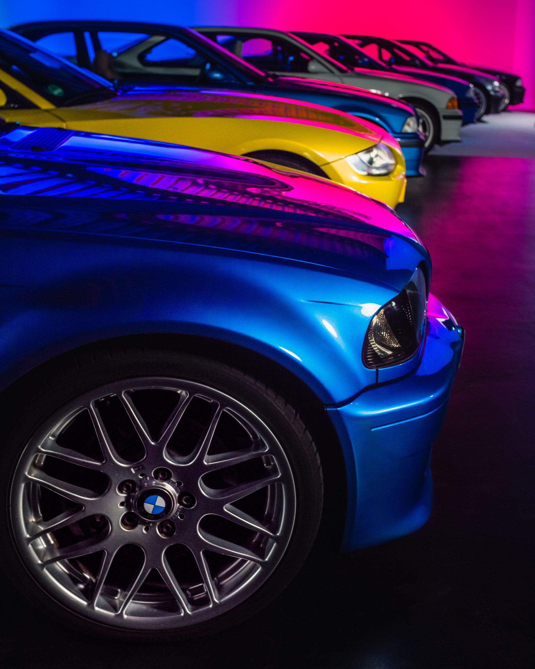 Blauer BMW M3 in magenta-blauem Neonlicht, dahinter ein gelbes Z4 M Coupé